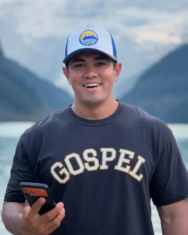 Timothy Leow smiling at Lake Louise, phone in hand